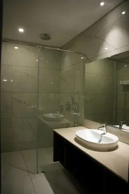 a bathroom with a sink and a glass shower at Alba Regency in Guruvāyūr