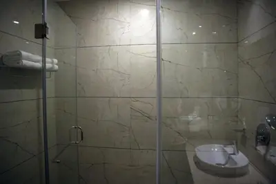a bathroom with a glass shower with a sink at Alba Regency in Guruvāyūr