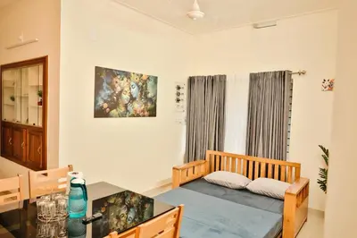 a room with a bed and a table and a painting at Nila Heavens - Spacious 5 BHK Homestay , ideal for families in Guruvāyūr