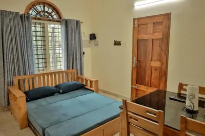 a bedroom with a bed with a desk and a door at Nila Heavens - Spacious 5 BHK Homestay , ideal for families in Guruvāyūr