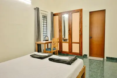 a bedroom with a bed and a table and a desk at Nila Heavens - Spacious 5 BHK Homestay , ideal for families in Guruvāyūr