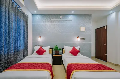 two beds in a hotel room with red pillows at AIRNEST Airport Residency in Nedumbassery
