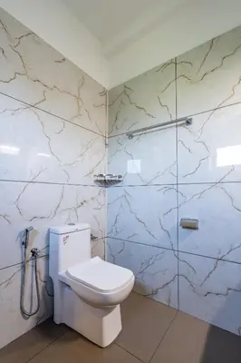 a bathroom with a white toilet and a shower at AIRNEST Airport Residency in Nedumbassery