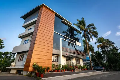 a building with a glass facade with palm trees at AIRNEST Airport Residency in Nedumbassery