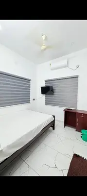 a white room with a bed and a table at Seascape Homestay Cherai Beach in Cochin