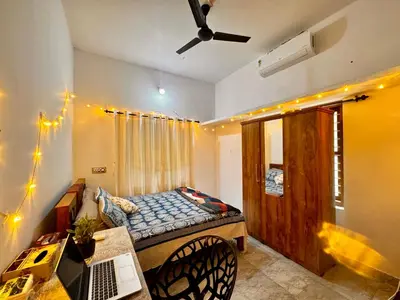 a room with a bed and a table and a laptop at Nirvana Stays Banasura, Wayanad in Wayanad