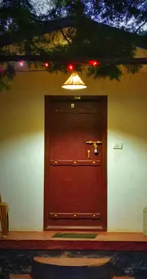 a large wooden door with a light above it at Madama Mudhouse Edenwood Retreats in Kanthalloor
