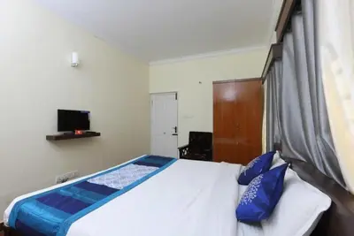 a bedroom with a bed with blue pillows on it at Ooty FernCrest in Ooty