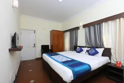 a bedroom with a large bed with blue pillows at Ooty FernCrest in Ooty