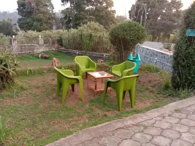four green chairs and a table in a yard at Ooty FernCrest in Ooty