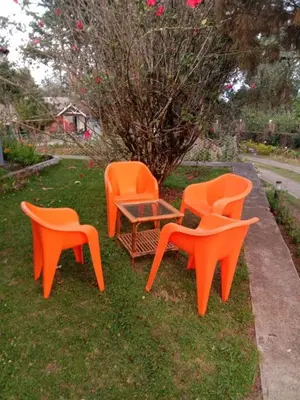 three orange chairs and a table in the grass at Ooty FernCrest in Ooty