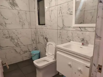 a bathroom with a white toilet and a sink at Thambaratty in Mysore