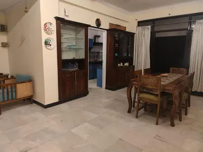 a dining room with a table and chairs and a kitchen at Thambaratty in Mysore