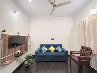 a living room with a blue couch and a tv at Kamadhenu Homestay, Comapact 1BHK OPP Mysore zoo, in Mysore