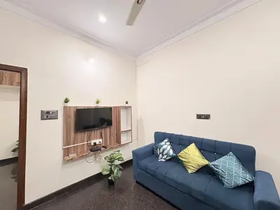 a living room with a blue couch and a tv at Kamadhenu Homestay, Comapact 1BHK OPP Mysore zoo, in Mysore