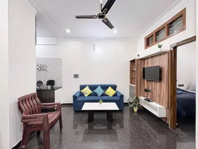 a living room with a blue couch and a tv at Kamadhenu Homestay, Comapact 2BHK OPP Mysore zoo, A in Mysore
