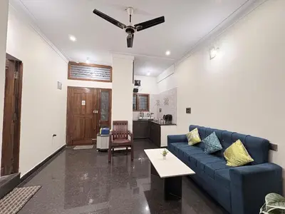 a living room with a blue couch and a table at Kamadhenu Homestay, Comapact 2BHK OPP Mysore zoo, A in Mysore