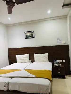 a bedroom with two beds and a wooden headboard at Hotel Malabar Grand in Perintalmanna