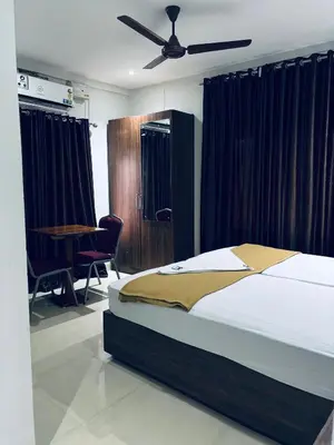 a bedroom with a bed and a ceiling fan at Hotel Malabar Grand in Perintalmanna