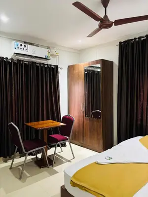 a bedroom with a bed and a table and chairs at Hotel Malabar Grand in Perintalmanna