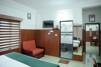 a bedroom with a bed and a chair and a mirror at TREE 9 Lounge -Cochin Airport in Nedumbassery