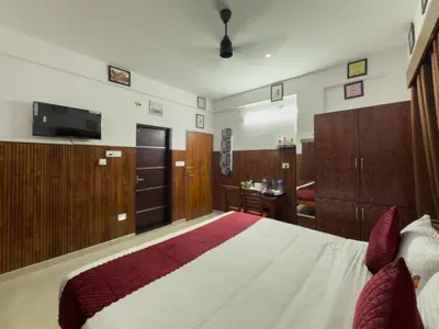 a bedroom with a bed with wooden cabinets and a television at TREE 9 Lounge -Cochin Airport in Nedumbassery