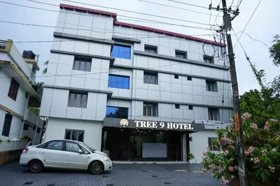 a white building with a car parked in front of it at TREE 9 Lounge -Cochin Airport in Nedumbassery