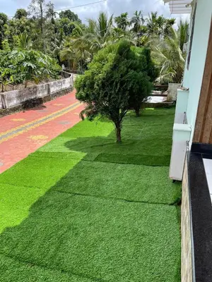 a green lawn with a tree on the side of a building at Wayanad Evergreen Farmhouse in Sultan Bathery