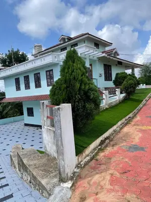 a white building with a tree in front of it at Wayanad Evergreen Farmhouse in Sultan Bathery