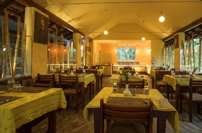a restaurant with wooden tables and chairs and windows at The Crescent Wayanad Heritage Pool Resort in Sultan Bathery