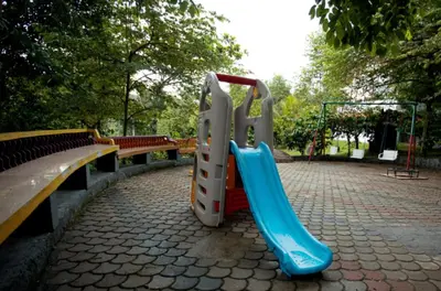 a playground with a slide in a park at The Crescent Wayanad Heritage Pool Resort in Sultan Bathery