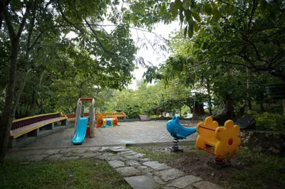 a park with a playground with play equipment and a bench at The Crescent Wayanad Heritage Pool Resort in Sultan Bathery