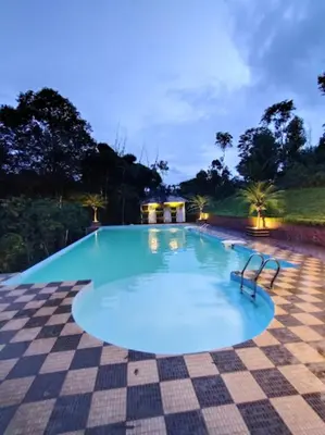 a large swimming pool at night with a checkered floor at The Crescent Wayanad Heritage Pool Resort in Sultan Bathery