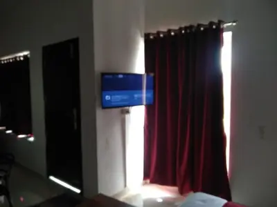 a room with a red curtain and a television at White house in Ooty
