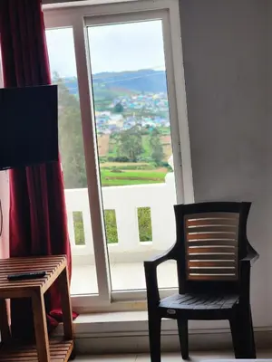 a chair sitting in front of a window with a view at White house in Ooty