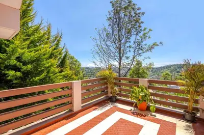 a balcony with a wooden fence and trees at Willostays Cloudhill ooty in Ooty