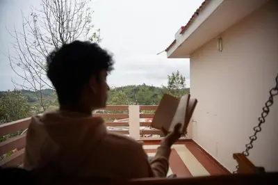a person reading a book on a balcony at Willostays Cloudhill ooty in Ooty