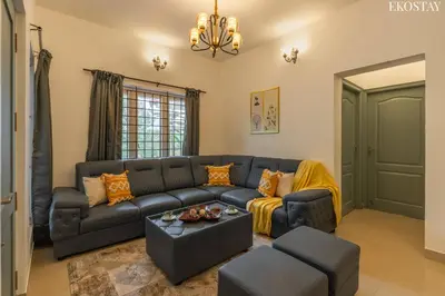 a living room with a black leather couch and chairs at EKOSTAY - Villa Eve in Ooty
