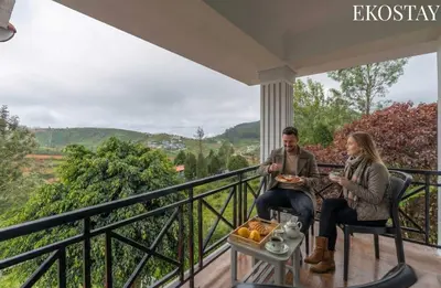 a man and woman sitting on a porch with food at EKOSTAY - Villa Eve in Ooty