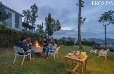 a group of people sitting around a fire in a yard at EKOSTAY - Skyfall Dew Drops in Ooty