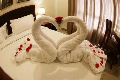 two swans made out of towels on a bed at Bhasuri Inn Guruvayoor in Guruvāyūr
