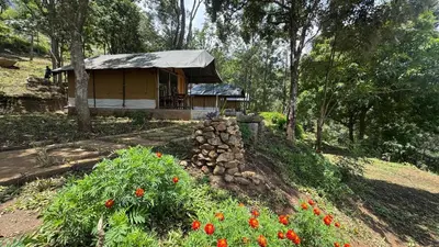 a small building with a roof in a field with flowers at Deshadan Jungle in Kanthalloor