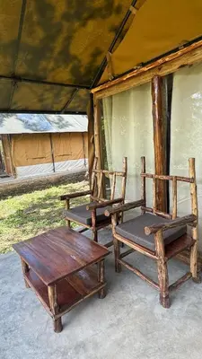 two wooden chairs and a table in a tent at Deshadan Jungle in Kanthalloor