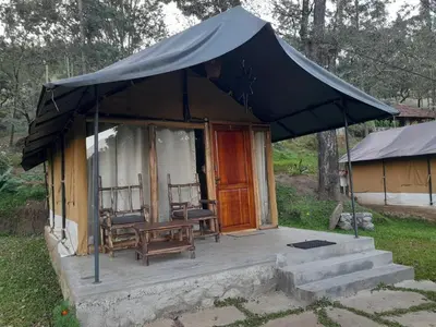 a tent with two chairs and a table on a porch at Deshadan Jungle in Kanthalloor