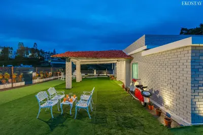 a patio with chairs and a table on a lawn at EKOSTAY - Casa Del Sol in Ooty