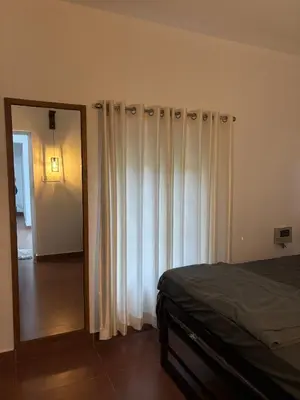a bedroom with white curtains and a mirror and a bed at Country Side Inn in Vayittiri