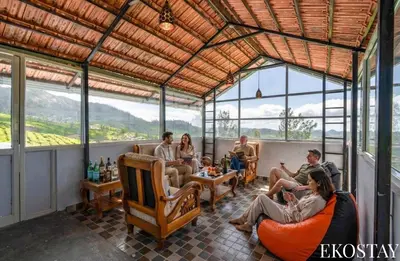 a group of people sitting in chairs in a room with windows at EKOSTAY - Garden Grove Villa in Ooty