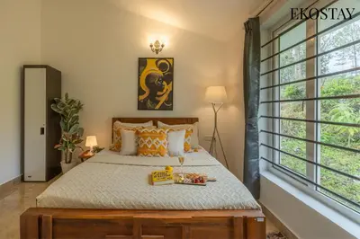 a bedroom with a bed and a large window at EKOSTAY - Skyfall Mist Villa in Ooty