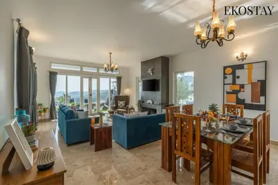 a living room with a blue couch and a table at EKOSTAY - Skyfall Mist Villa in Ooty