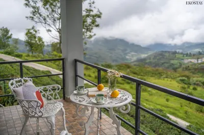 a table and chairs on a balcony with a view at EKOSTAY - Skyfall Elysium Villa in Ooty